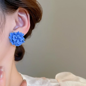 Close-up of blue resin flower stud earring worn by a model for a fresh summer look