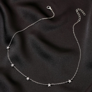 Dettaglio della collana con stelle argentate e zirconi su sfondo di seta nera di lusso