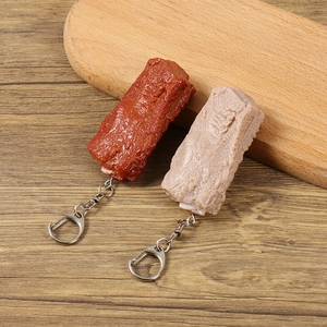 Realistische PVC-Schweinerippchen-Schlüsselanhänger in zwei Farben auf Holzgrund