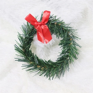 Close-up of green PVC pine needle wreath with a red ribbon bow for Christmas decor