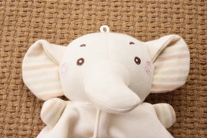 Macro shot of organic cotton baby elephant pacifier toy with embroidered face details