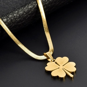 Macro detail of a gold clover pendant with sunburst texture on a sleek snake chain
