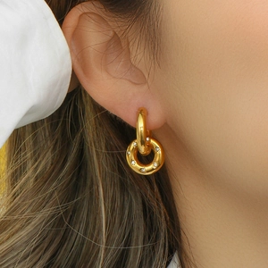 Detailed view of gold plated hoop earrings with micro rhinestones on a female model