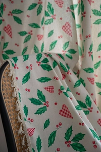 Close-up of Christmas curtain fabric with holly leaves and red berry patterns with tassels