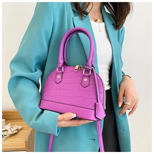 Close-up of purple crocodile pattern shell bag featuring gold zippers and double handles