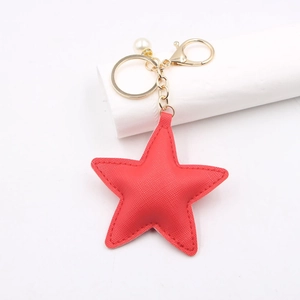 Detail of red PU leather star keychain with gold hardware and faux pearl accent