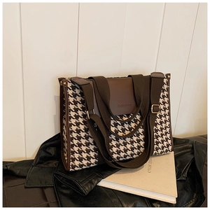 Detail of vintage houndstooth tote bag with brown leather trim and handle on art book