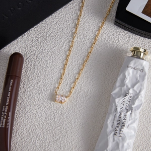 Detailed shot of golden paperclip chain necklace with dual rectangular zircon pendants
