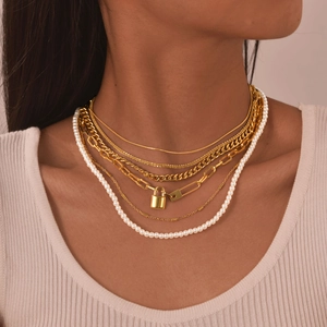Layered gold necklace set with pearls and lock pendant on a female model neck