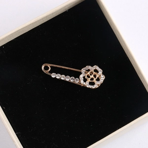 Close-up of golden flower brooch with clear rhinestones on a black velvet box