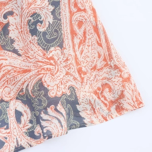 Gros plan sur un tissu léger à imprimé cachemire orange et gris sur fond blanc pur