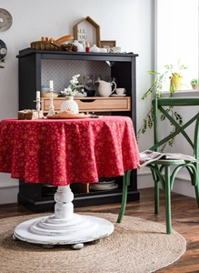 Detail of red round tablecloth with gold snowflake patterns on a vintage white table