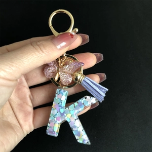 Detailed macro of resin letter K keychain with colorful sequins and butterfly charm