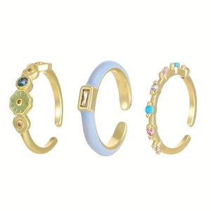 Detailed close-up of three-piece adjustable gold ring set with colorful enamel and crystals