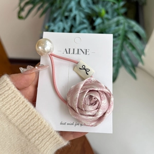 Detailed shot of silk rose scrunchie with large faux pearl on elegant display card