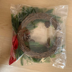 Close-up of Christmas wreath with natural pine cones and red ribbon on rattan base