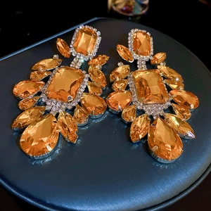Detailed shot of large amber drop earrings with geometric gems and crystal inlay