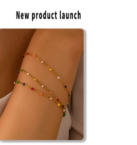 Detail of a multi-layer gold bracelet featuring colorful beads on a model's wrist