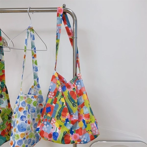 Three minimalist printed cotton crossbody bags in colorful geometric patterns on a rack