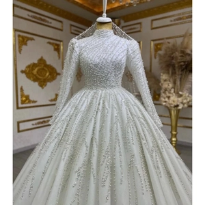 Detailed view of luxury bridal gown featuring intricate pearl beadwork and long sleeves