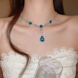 Dettaglio di collana di lusso con pendente in pietra blu a pera e diamanti su modella