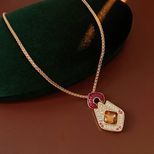Detail of vintage gold necklace with amber stone and red enamel on velvet display