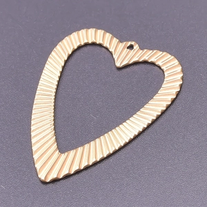 Detailed view of 18k gold plated heart pendant with radiating textured wave pattern