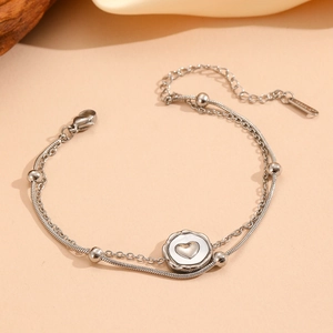 Macro detail of silver stainless steel double-layer bracelet with heart pendant and clasp