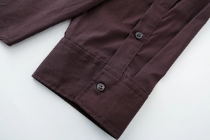 Detailed close-up of dark brown poplin shirt cuff with two grey round buttons