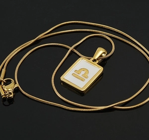 Macro shot of 18K gold plated Libra pendant on sleek snake chain with white enamel