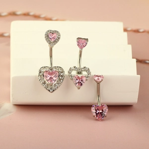 Detailed view of silver heart navel rings with pink cubic zirconia on a white stand