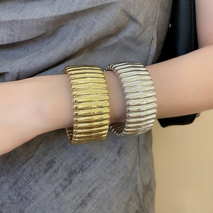 Detailed view of wide textured cuff bracelets in gold and silver finish on wrist