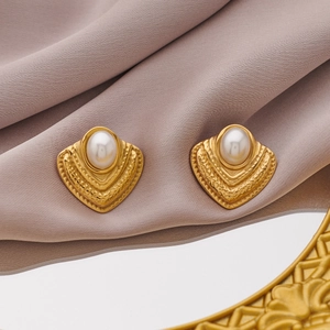 Detail of vintage gold-plated earrings with radiant texture and centered pearls