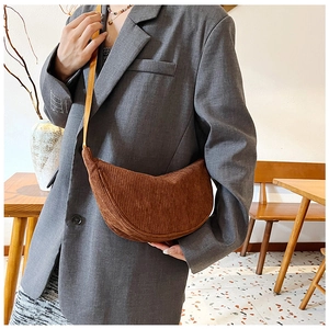 Brown corduroy crescent shoulder bag shown in a cozy indoor setting for daily commute