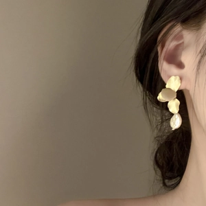 Golden flower petal earrings with baroque pearls on a model, showcasing elegant style