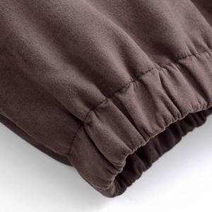 Detail of dark brown suede jacket featuring elastic cuffs and premium stitching