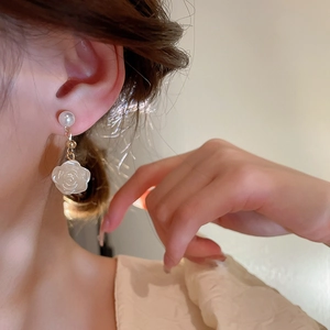 Elegant acrylic camellia flower and faux pearl drop earrings in creamy white on a model