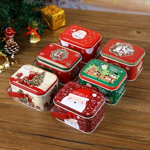 Variety of Christmas tin gift boxes with Santa and reindeer motifs on a festive wooden surface