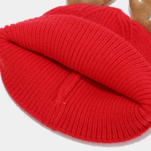 Close-up of red ribbed knit Christmas hat with brown plush reindeer antlers detail