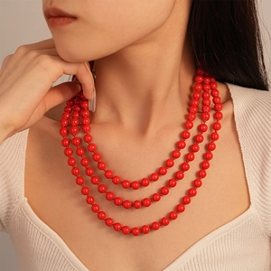 Detailed close-up of a three-layer vibrant red pearl necklace on a model for autumn style