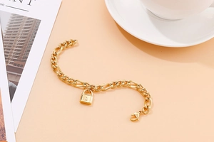 Detailansicht eines goldenen Gliederkettenarmbands mit Schlossanhänger auf dem Tisch