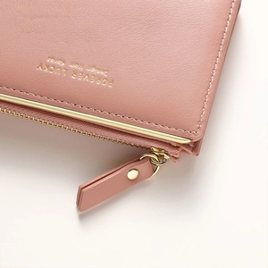 Detailed macro view of light pink leather wallet texture with gold zipper and lettering