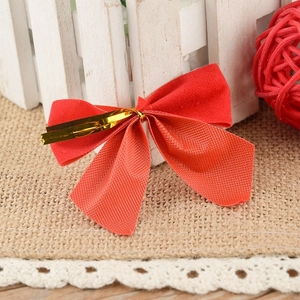 Red flocked bowknot Christmas tree ornament with gold tie on a rustic burlap background