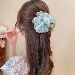 Detail einer hellgrünen Chiffon-Blumen-Haarklammer in langem Haar mit eleganten Blütenblättern