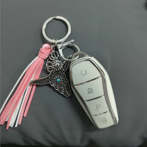 Detail of bohemian bull head keychain with turquoise stones and a pink tassel charm
