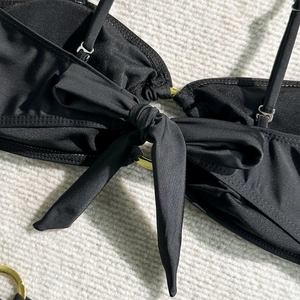 Gros plan du haut de bikini noir avec nœud papillon et anneaux métalliques dorés décoratifs