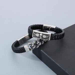 Detail of men's black braided leather bracelets with winged skull and stainless steel hardware