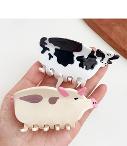 Detailed view of handmade cow and pig patterned acetate hair claws with smooth glossy finish