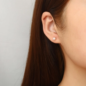Elegant stainless steel pearl and zircon stud earrings worn by a female model
