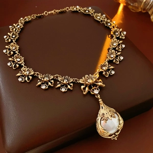 Détail d'un collier vintage doré à fleurs avec perles et cristaux sur du cuir